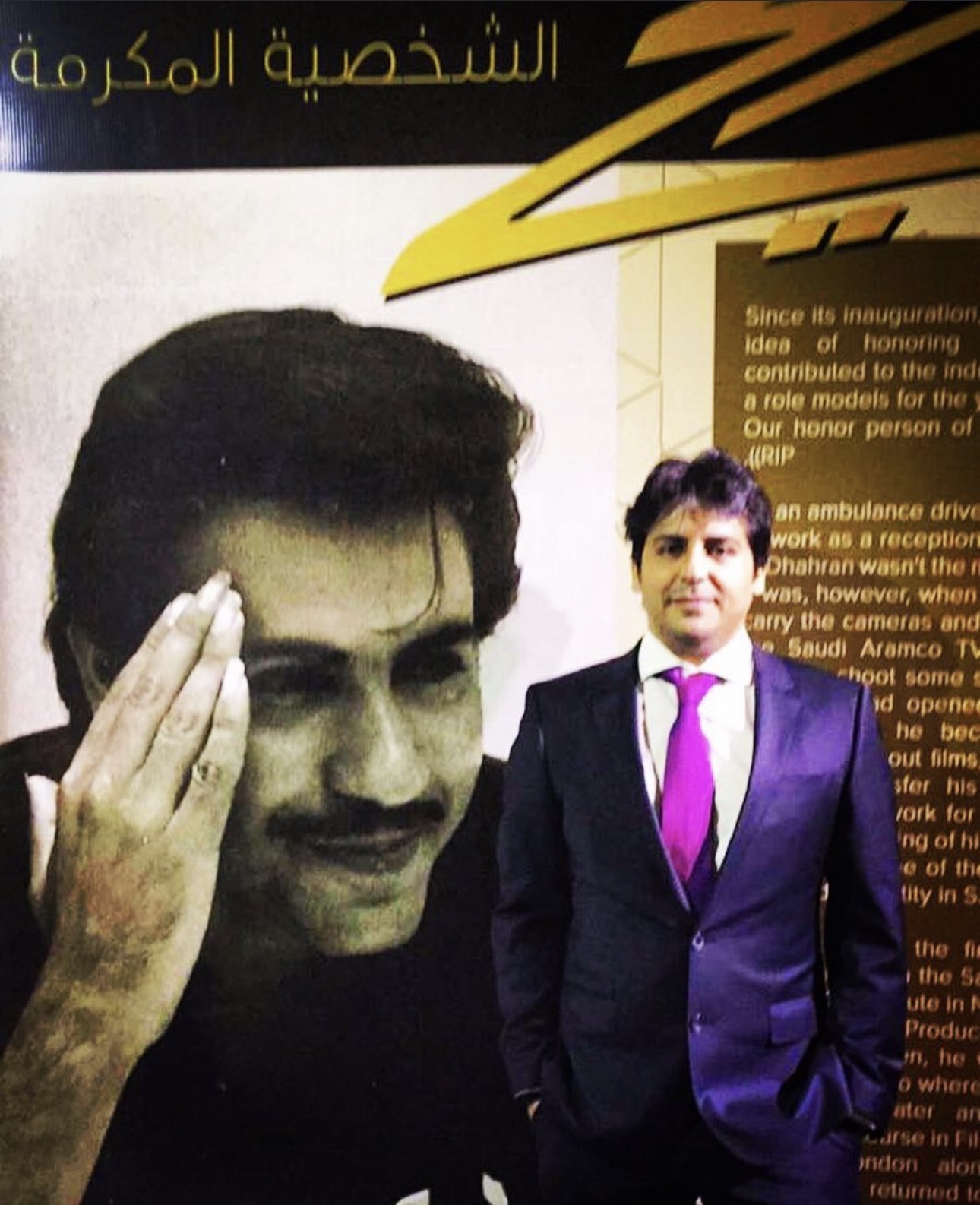 Abdulaziz Alfuraih beside a large portrait of his father, director Saad Alfuraih, at a tribute event