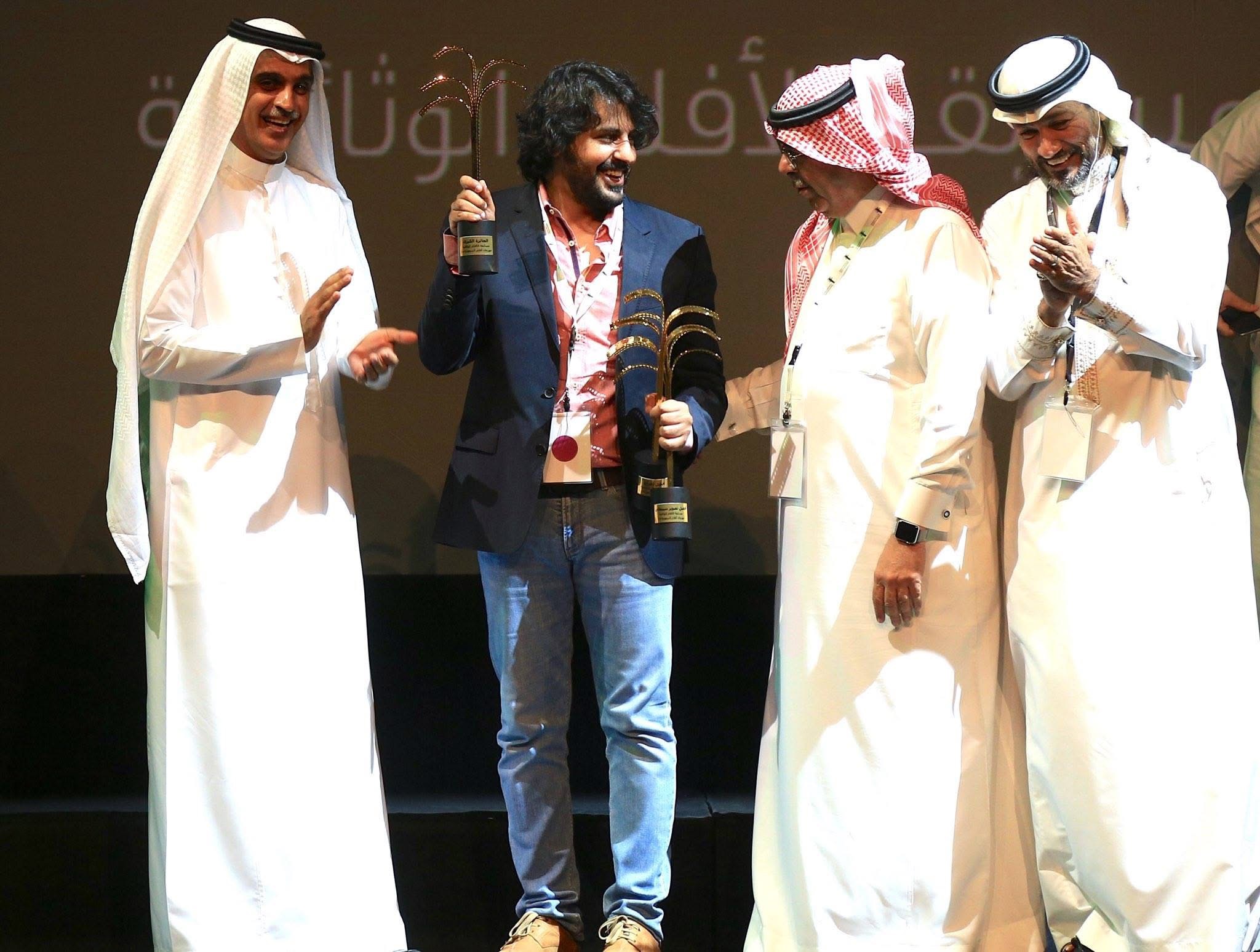 Abdulaziz Alfuraih holding the awards for Building 20 on stage at the Saudi Film Festival