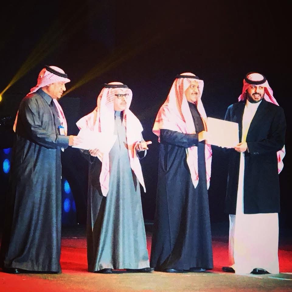 Abdulaziz Alfuraih receiving a certificate of recognition on stage